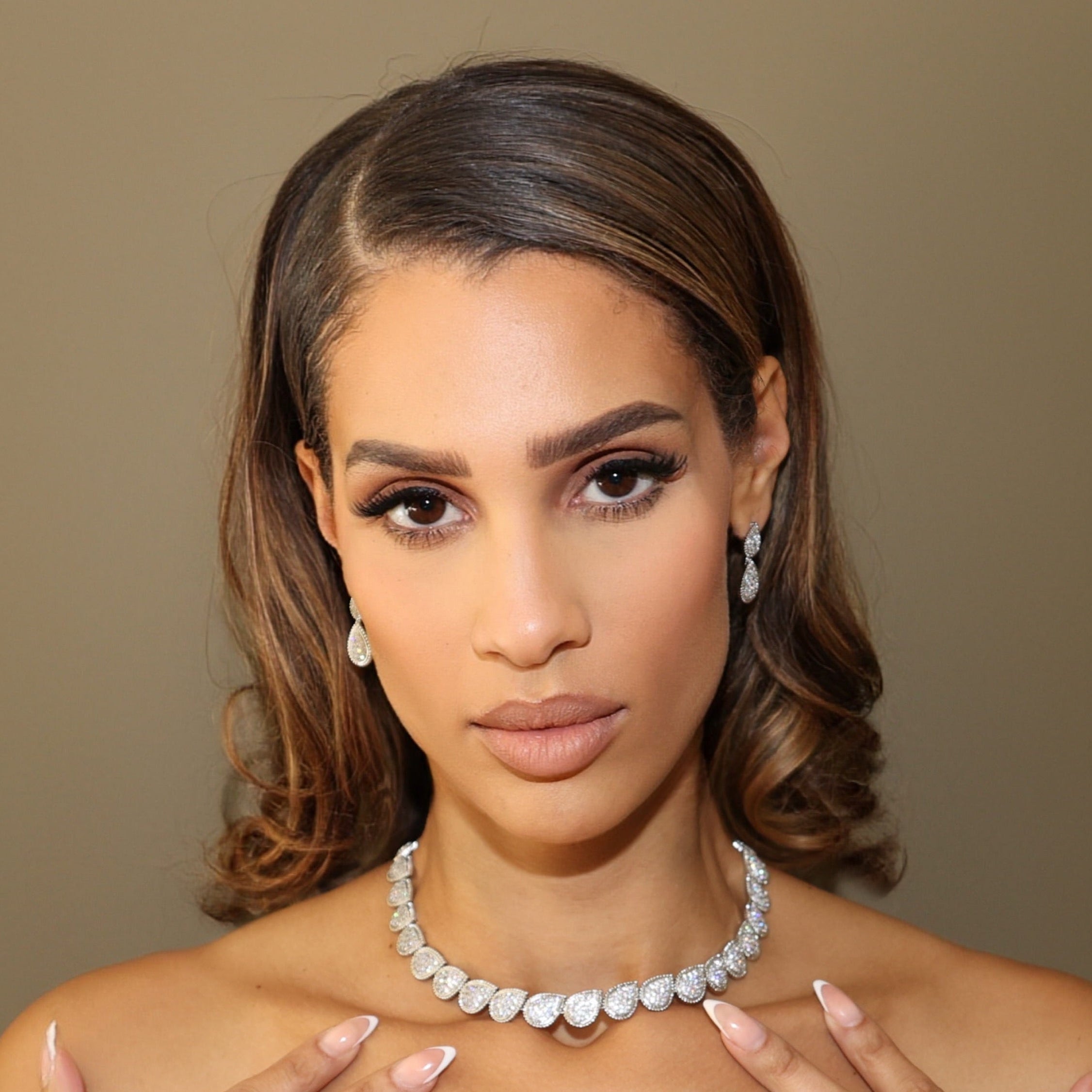 Woman wearing a black dress with the LUNA COLLECTION jewelry against a brown background